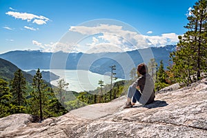 Woman Hiker relaxing on the top of a Mountain and admiring the Scenic Landscape