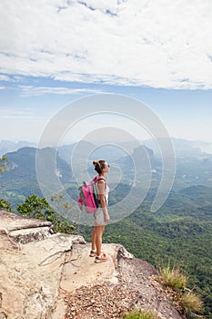 Woman hiker relaxing on top of a mountain and enjoying the view