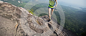 Woman hiker running up on mountain peak cliff edge