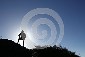 Woman hiker in silhouette standing on top mountain