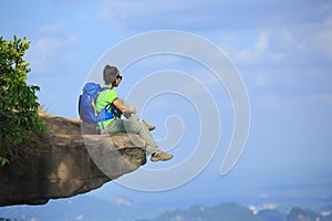 woman hiker sit on mountain top cliff enjoy the view