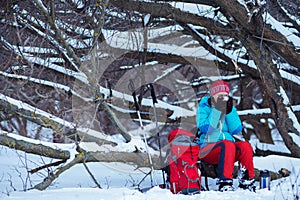 Woman, hiker sits drinks coffee in winter forest