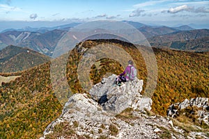 Woman hiker sitting on th rock on top of the hill Klak and looking on beautiful mountain landscape under