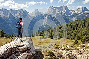 Woman hiker standing on stone rock and looking at mountains