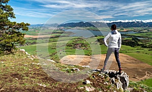 Woman hiker standing on top of the hill and looking on beautiful nature with lake and snowy mountains in region Liptov at Slovakia