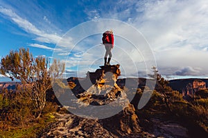 Woman hiker standing on top of rock precipice with grand views