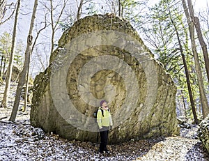 Woman hiker stops beside huge boulder to marvel at wilderness en