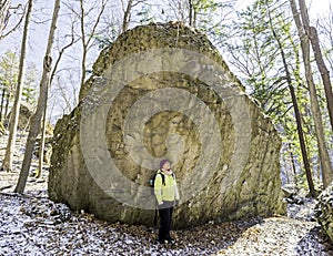 Woman hiker stops beside huge boulder to marvel at wilderness en photo