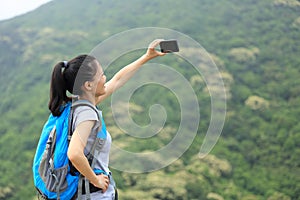 Woman hiker taking photo with cellphone