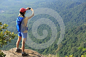 Woman hiker taking photo with cellphone hiking on mountain peak