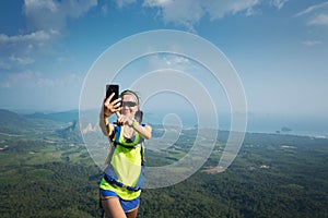 Woman hiker taking photo with cellphone hiking on mountain peak
