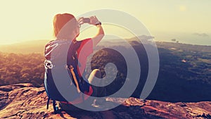 Woman hiker taking photo with cellphone on mountain top
