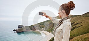 Woman hiker taking photo in front of ocean view landscape