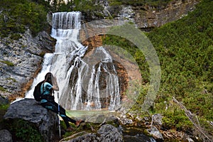 Woman hiker taking photo of waterfall