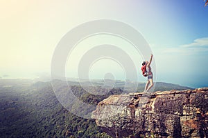 Woman hiker taking photos with cellphone at mountain peak