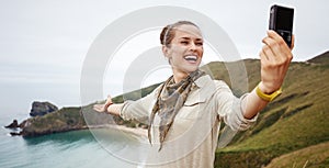 Woman hiker taking selfie in front of ocean view landscape