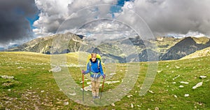 Woman hiker travels in Pyrenees Mountains in Andorra and Spain. Nordic walking, recreation and trekking along GR11 path