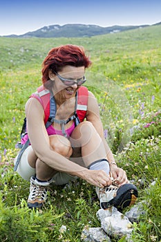 Woman hiker tying the shoelaces in mountains