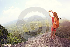 Woman hiker use smartphone taking photo on seaside mountain top