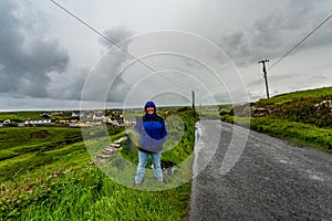 Woman hiker with the village of Doolin in the background starting the coastal walk route to the Cliffs of Moher