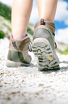 Woman hiker walk on a rocky ground. Sunny day.Trekking boots.Lens flare. Succesful backpacker. Stone. Step