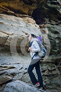 Woman hiker walking with backpack big rock at background