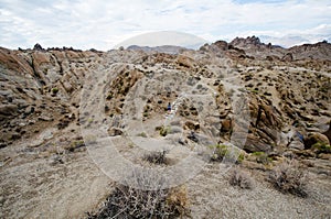 Woman hiker walks along a dirt trail through the Alabama Hills to the The Mobius Arch Loop Trailhead