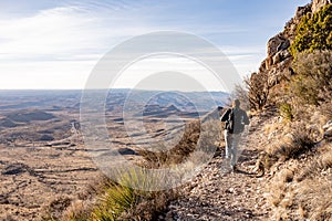 Woman Hikes Along Shelf High Above Desert Road Below