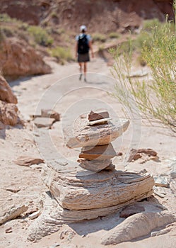 Woman Hikes Behind Cairn in Desert