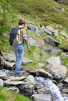 Woman hiking in the Alps, crossing little stream