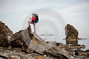 Woman with hiking equipment goes through stoney coast