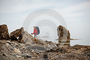 Woman with hiking equipment travelling through stoney coast