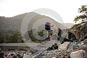 Woman with hiking equipment walking through stoney coast