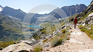 Woman hiking on footpath in idyllic mountain landscape with blue lake, high mountain peak and glacier. Summer adventures on the Al