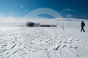 Woman hiking in Krkonose mountains towards Lucni bouda on a sunny winter day, Czech republic