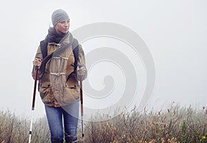 Woman, hiking and nature with trekking sticks, winter and support for fog trail in mountain. Athlete, backpack and