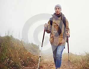 Woman, hiking and outdoor with trekking sticks, winter and support for fog trail in mountain. Athlete, backpack and