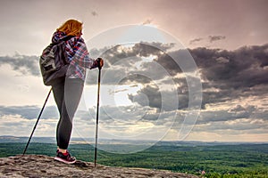 Woman hiking silhouette on mountains, sunset and fall landscape. Female hiker looking over edge at beautiful Sunset