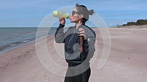 Woman with hiking sticks and water bottle near beach