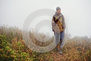 Woman, hiking and thinking in countryside for trekking, sticks and planning by fog trail in mountain. Athlete, backpack