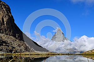 The woman hiking to Riffelsee lake in front of Matterhorn and cl