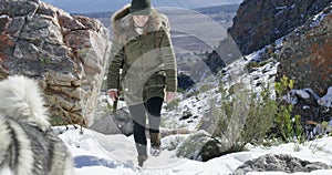 Woman, hiking trail and dog in winter, snow and playing on mountain, animal and holiday. Vacation, pet and Alaskan