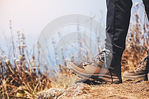 A woman hiking with trekking boots on the top of mountain