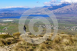 Woman hiking up the mountain paths to the top, with beautiful views of the landscape in the background