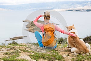 Woman hiking walking with dog on sea landscape