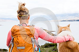 Woman hiking walking with dog on sea landscape