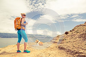Woman hiking walking with dog on sea landscape