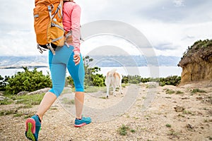 Woman hiking walking with dog on seaside trail