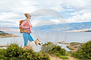 Woman hiking walking with dog on seaside trail