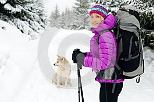 Happy woman walking in winter forest with dog